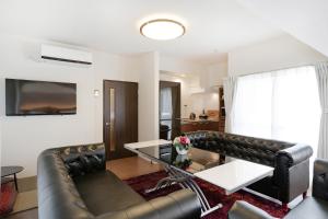 een woonkamer met een leren bank en een tafel bij Ideal Fukushima in Osaka