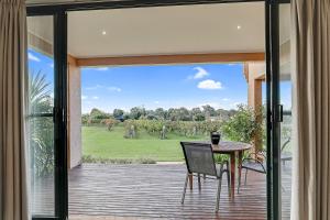 an open glass door to a patio with a table and chairs at Tuileries at De Bortoli Rutherglen in Rutherglen