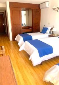 2 bedden in een hotelkamer met houten vloeren bij Hotel Alhambra in Punta del Este