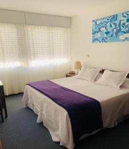 um quarto com uma cama grande e um cobertor roxo em Hotel Alhambra em Punta del Este
