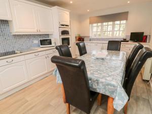 a kitchen with a table with black chairs and white cabinets at Coquet View Cottage in Morpeth