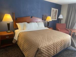 Andy Griffith Parkway Inn في ماونت إيري: غرفة فندقية بسرير كبير وكرسي