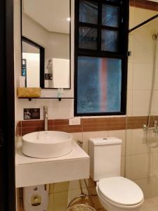 a bathroom with a sink and a toilet and a window at The Henry Resort Taramindu Laiya in Batangas City