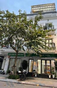 a white building with a tree in front of it at Tropical Villa Halong in Ha Long