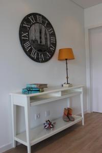 um relógio pendurado numa parede acima de uma mesa branca em Berna Apartment em Funchal
