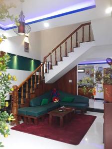 een woonkamer met een groene bank en een trap bij BOBE Homestay in Hội An