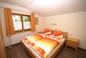 ein Schlafzimmer mit einem Bett mit einer bunten Decke und einem Fenster in der Unterkunft Haus Sommerstein in Maria Alm am Steinernen Meer