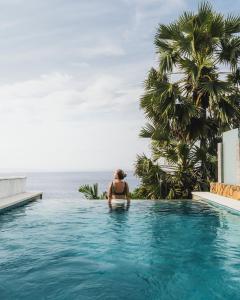 a woman in a swimming pool next to the ocean at Shunyata Villas Bali in Seraya