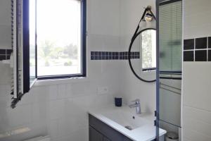 ein weißes Bad mit einem Waschbecken und einem Fenster in der Unterkunft Holiday Home, Neville-sur-Mer in Néville-sur-Mer