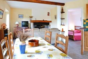a living room with a table with chairs and a fireplace at Stone cottage with shared pool, Chambonas in Chambonas