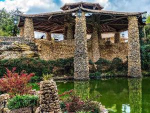 un gran edificio de piedra con un estanque delante de él en La Mariposa San Antonio - New! 5 min to Downtown!, en San Antonio