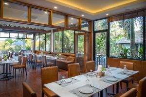a restaurant with tables and chairs and large windows at Amatak Boutique Hotel in Siem Reap
