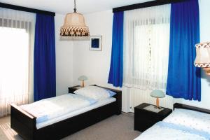 2 Betten in einem Schlafzimmer mit blauen Vorhängen in der Unterkunft Apartment in Oberdrauburg with parking space in Oberdrauburg