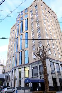 ein hohes Gebäude mit einem Baum davor in der Unterkunft Kurashiki Royal Art Hotel in Kurashiki