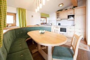 a kitchen with a wooden table and a green couch at Holiday flats B rlerhof K nigsleiten in Königsleiten