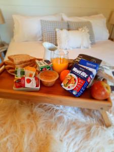 a tray with breakfast foods and a drink on a bed at Tawa Cove Cabins in Endeavour Inlet