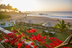 a view of a beach with red flowers and umbrellas at Villa Tanderra in Tangalle +166 photos