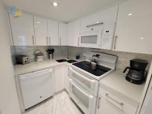 een witte keuken met een fornuis en een magnetron bij Deluxe Beach Resort - HORA RENTALS in Miami Beach