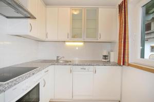 uma cozinha com armários brancos, um lavatório e uma janela em holiday home, Itter em Itter