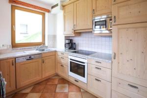 a kitchen with wooden cabinets and a sink and a window at Holiday flat B rlerhof XXL K nigsleiten in Königsleiten