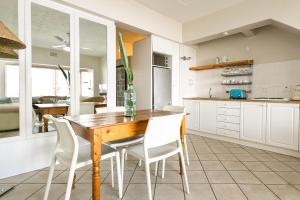 cocina con mesa de madera y sillas blancas en Village Apartments - Camps Bay, en Ciudad del Cabo
