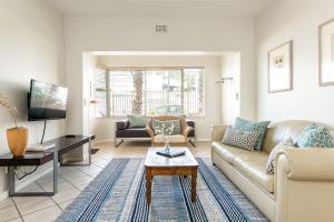 una sala de estar con un sofá y una mesa en Camps Bay Village - Village Apartments, en Ciudad del Cabo 45 fotos más