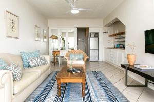 una sala de estar con un sofá y una mesa en Camps Bay Village - Village Apartments, en Ciudad del Cabo