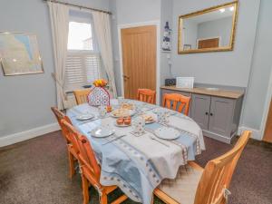 jadalnia z niebieskim stołem, krzesłami i lustrem w obiekcie Ambler's Rest Cottage w mieście Amble