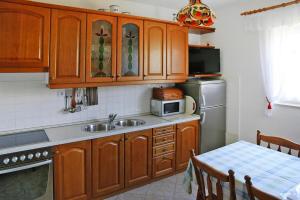 eine Küche mit Holzschränken, einer Spüle und einem Tisch in der Unterkunft Apartments Adelheid, Biograd in Biograd na Moru