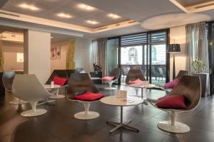 a waiting room with chairs and tables with red pillows at Le Rex Hôtel in Tarbes