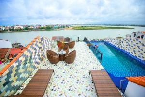 a swimming pool on top of a building next to a body of water at Rockmouse Centre River Villa Hoi An in Hoi An +22 photos