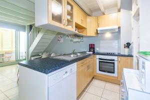 eine Küche mit weißen Geräten und Holzschränken in der Unterkunft Purple - Duplex cosy en plein cœur de l'Hermitage, proche du lagon in L'Ermitage-Les-Bains + 4 Fotos