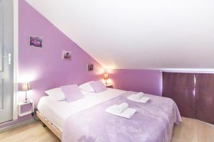 ein lila Schlafzimmer mit 2 Betten und Handtüchern darauf in der Unterkunft Purple - Duplex cosy en plein cœur de l'Hermitage, proche du lagon in L'Ermitage-Les-Bains