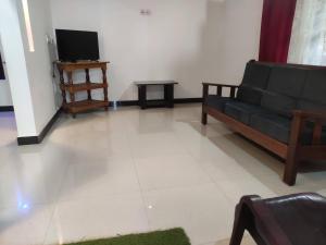 a living room with a black couch and a tv at Spices Garden Homestay & Plantation Tour in Madikeri