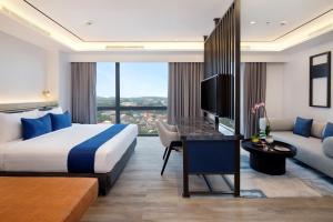 a hotel room with a bed and a tv and a couch at Hotel Aruss Semarang in Semarang