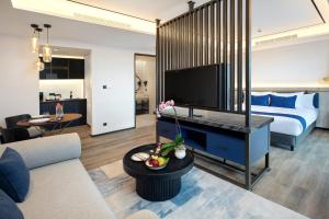 a room with a bed and a living room with a tv at Hotel Aruss Semarang in Semarang