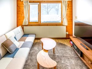 a living room with a couch and a table and a tv at Rusutsu Lodges Pension Lilla Huset in Rusutsu