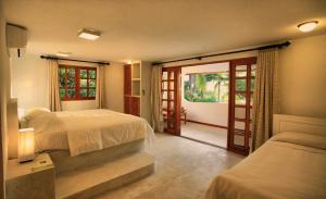 a bedroom with two beds and a door to a balcony at Hotel Tropico Latino in Santa Teresa Beach