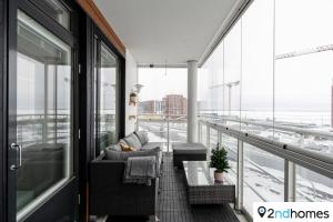 ein Balkon mit einer Couch und einem Tisch auf einem Gebäude in der Unterkunft Homelike 1BR Apartment with Sauna, Balcony & Free Parking in Tampere