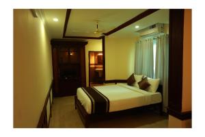 ein Schlafzimmer mit einem Bett in einem Zimmer in der Unterkunft CORRIDOR CALICUT Airport Hotel in Kondotti