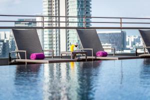 a swimming pool with chairs and a view of a city at Hotel Traveltine in Singapore