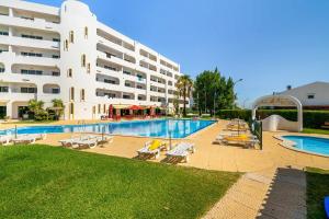 a swimming pool with lounge chairs and a large building at Artens 407 Dream Lodging in Albufeira