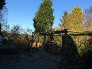 a wooden pergola in a yard with trees at Laburnum Cottage Guest House in Knutsford