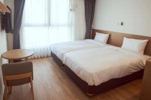 a bedroom with a bed and a table and a window at Kenny Stay Busan Gijang in Busan