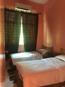 two beds in a room with a window at Homestay Tok Penghulu in Kuantan