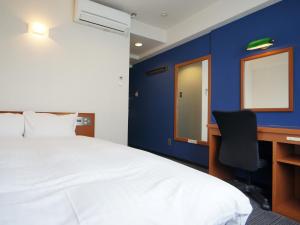 a bedroom with a bed and a desk with a computer at GR Hotel Ginzadori in Kumamoto