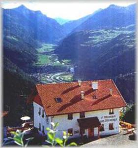 une maison avec un toit rouge au sommet d'une montagne dans l'établissement Wirtshaus zum Wiesejaggl, à Kaunerberg