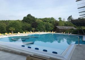 a large swimming pool with chairs and blue water at Am Living Garden in Bad Pyrmont