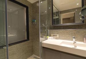 グルガオンにあるAIR by Ahuja Residencesのバスルーム(洗面台、ガラス張りのシャワー付)