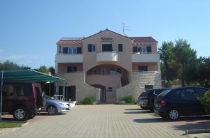 a building with cars parked in a parking lot at Apartmani Kristiana in Jezera